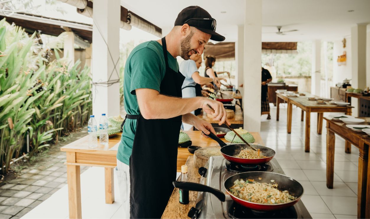 A chef prepares a meal in an open-air kitchen setting in Bali