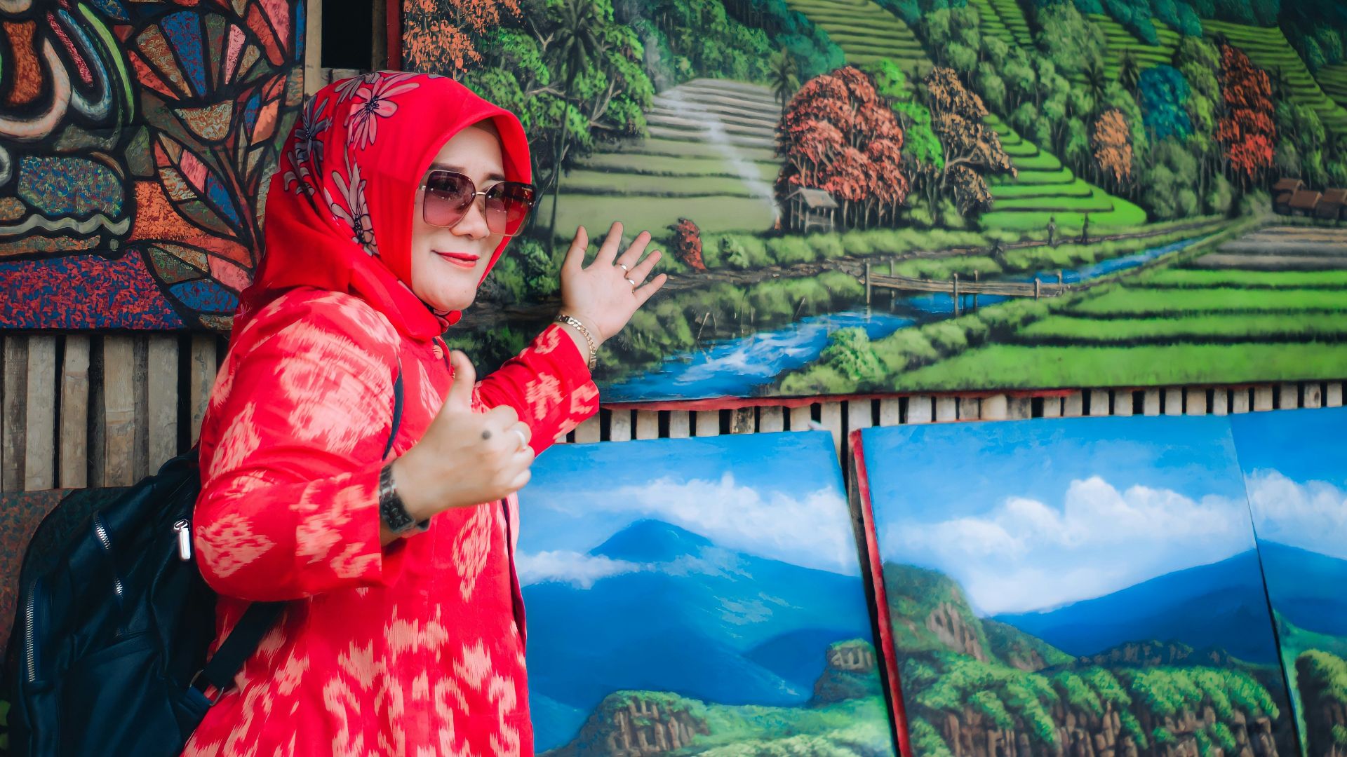 a person wearing a red scarf and glasses standing in front of a painting