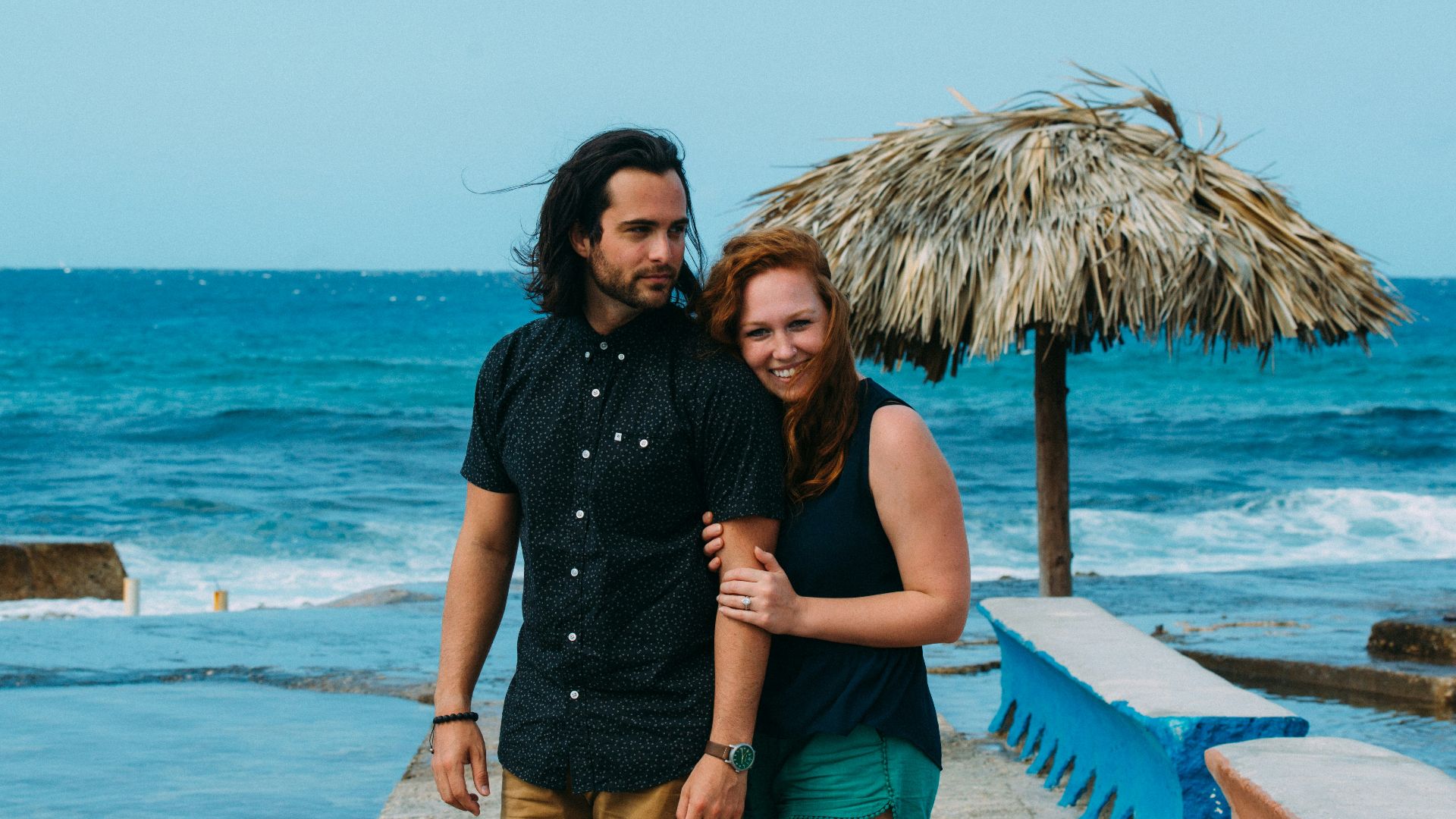 Couple walking on a pier by the ocean.