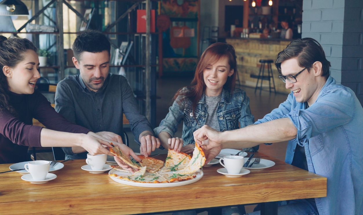 A group of friends enjoying pizza and coffee in a casual cafe