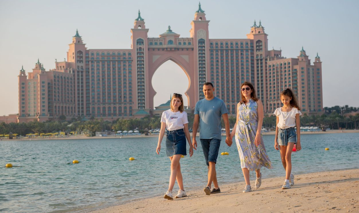 A family walking on a beach with the iconic Atlantis, The Palm hotel in Dubai
