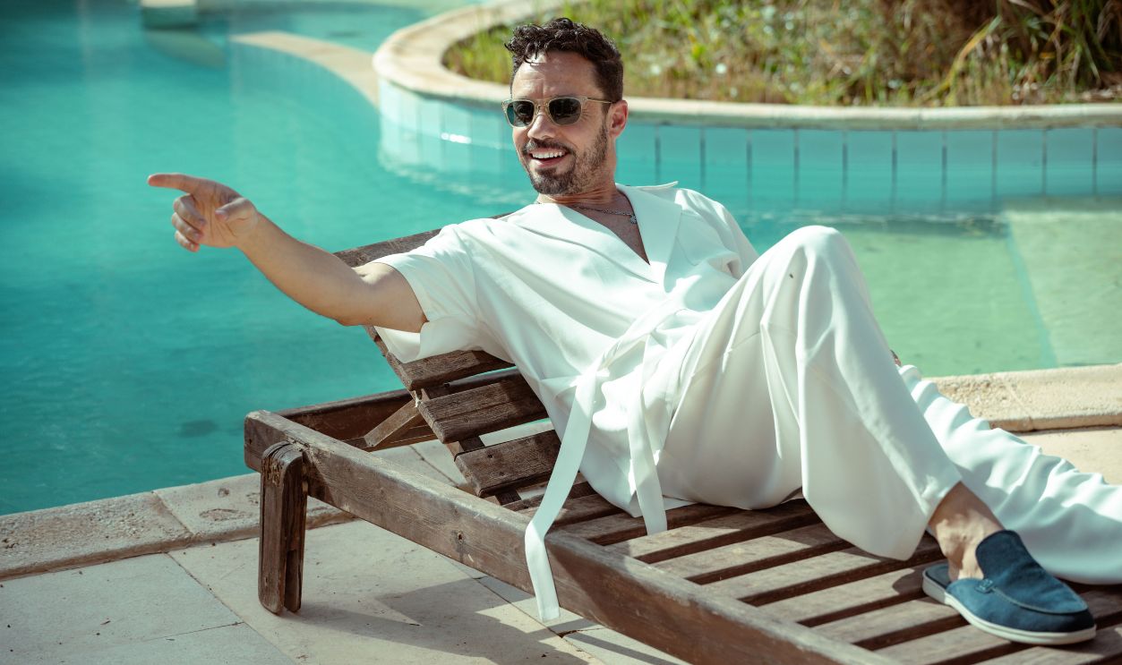 Man in white attire lounging on a sunbed by a pool