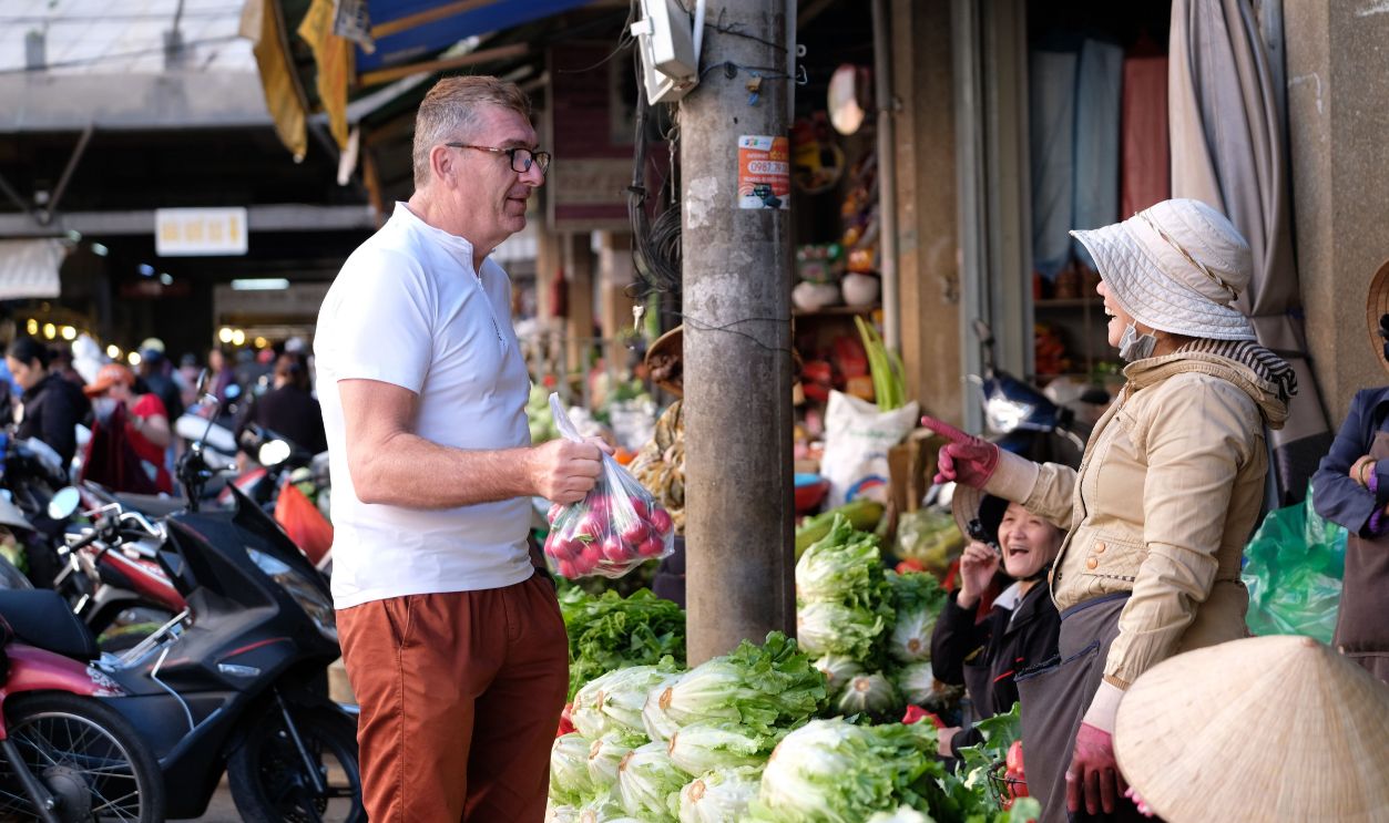 A vibrant scene at a bustling Vietnamese market with people interacting and fresh produce on display