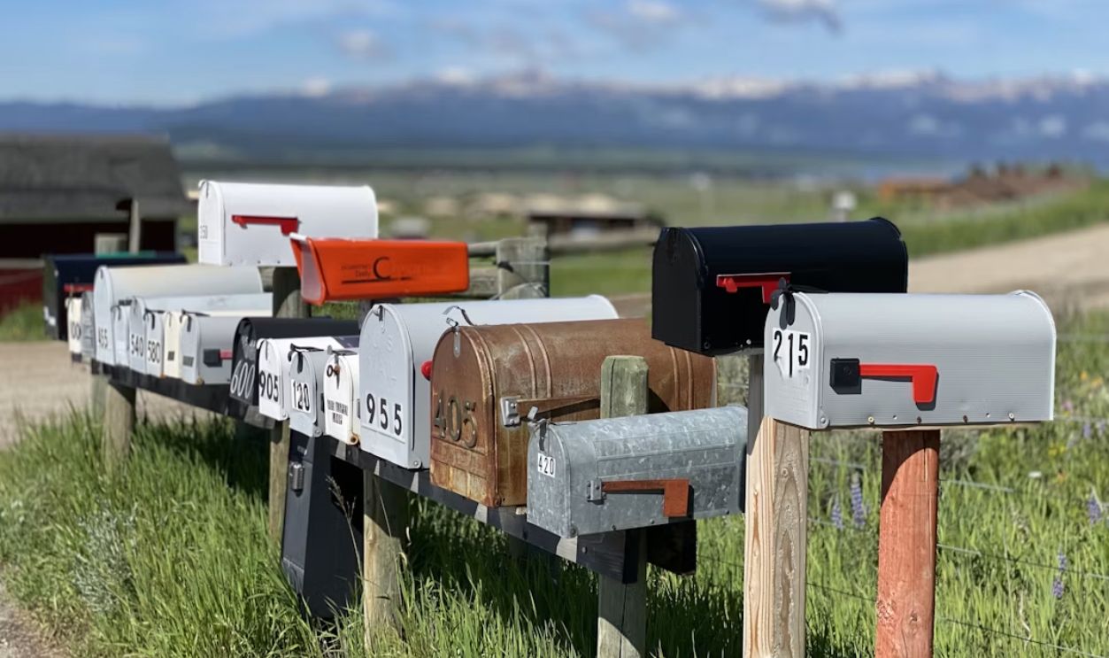 white and red mail box on brown wooden fence