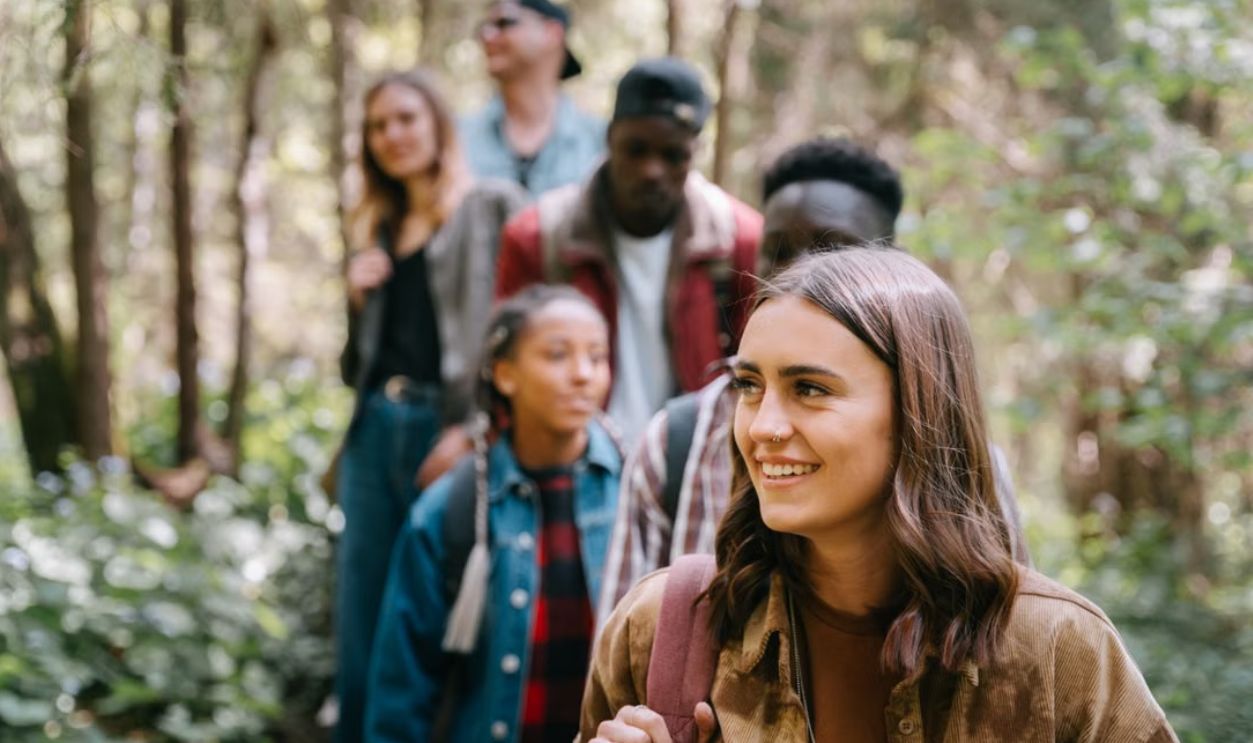 Five friends enjoying a hike through a lush, green forest on a sunny day