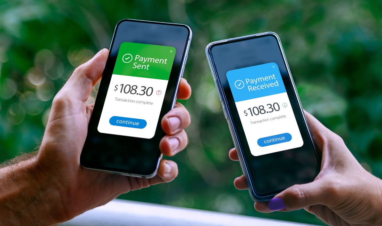 Two smartphones held by a woman and a man showing sending and receiving payments through a digital wallet application on a mobile phone. Bank transfer concept. Digital money.