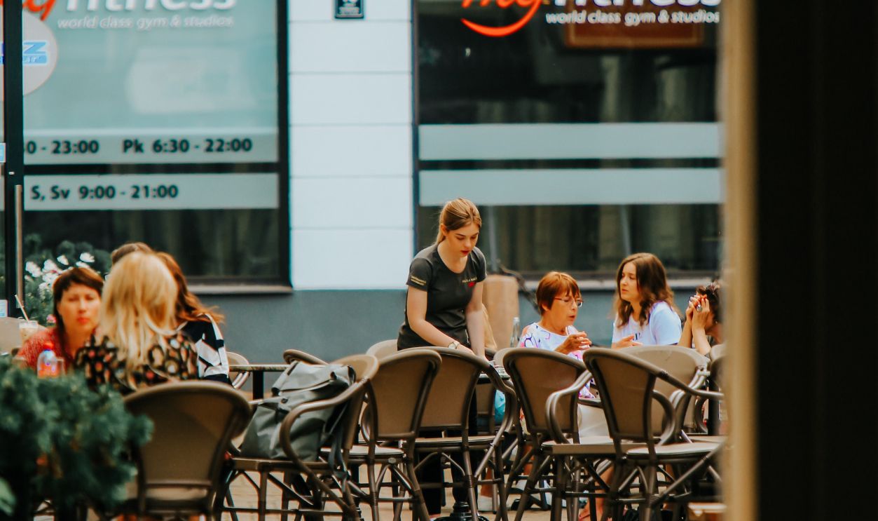 A lively outdoor cafe with people enjoying meals, featuring elegant chairs and tables.