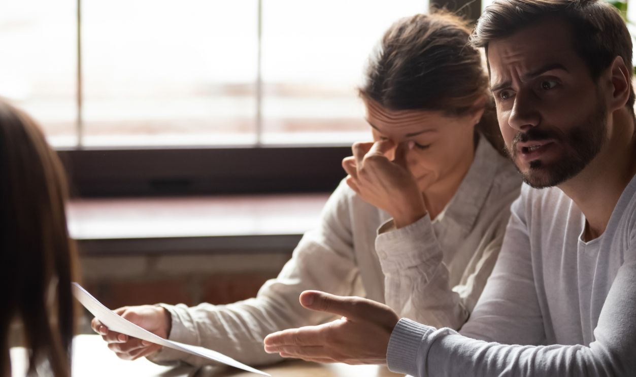 Diverse millennial people sitting at table in office indignant man accusing incompetent unqualified woman colleague pointing on financial report with mistakes, lack of education and knowledge concept