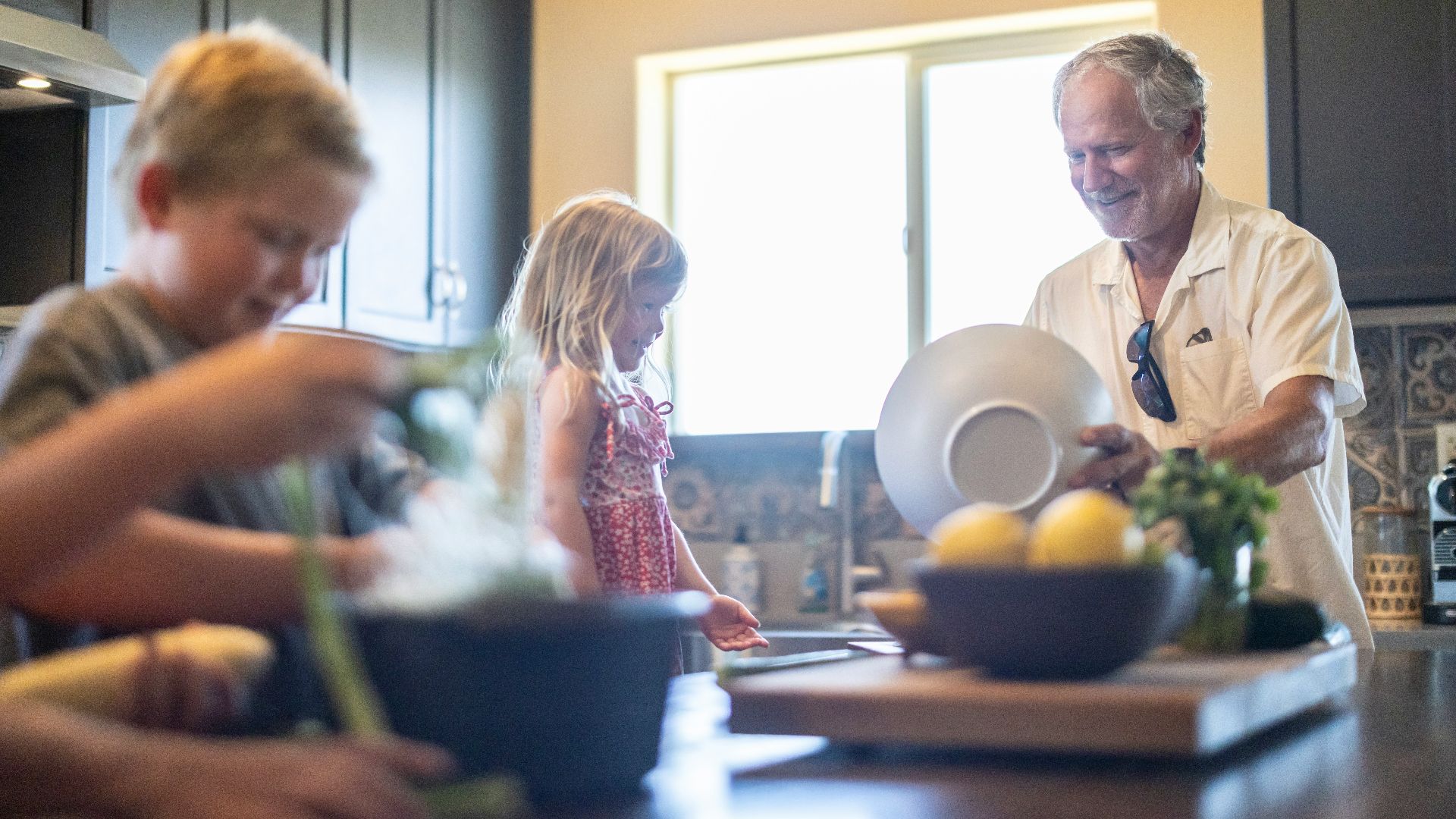 Grandfather and grandchildren prepare food in kitchen