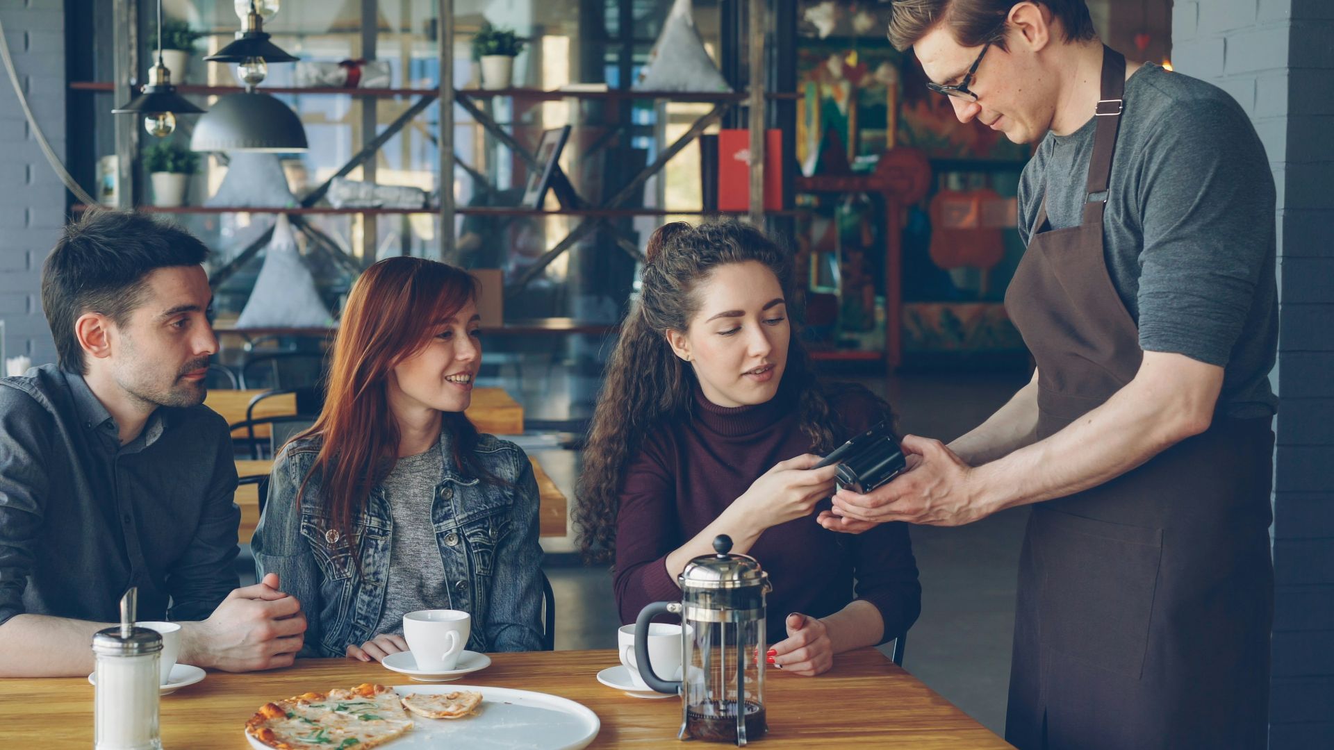 A waiter is taking a payment at a cafe.