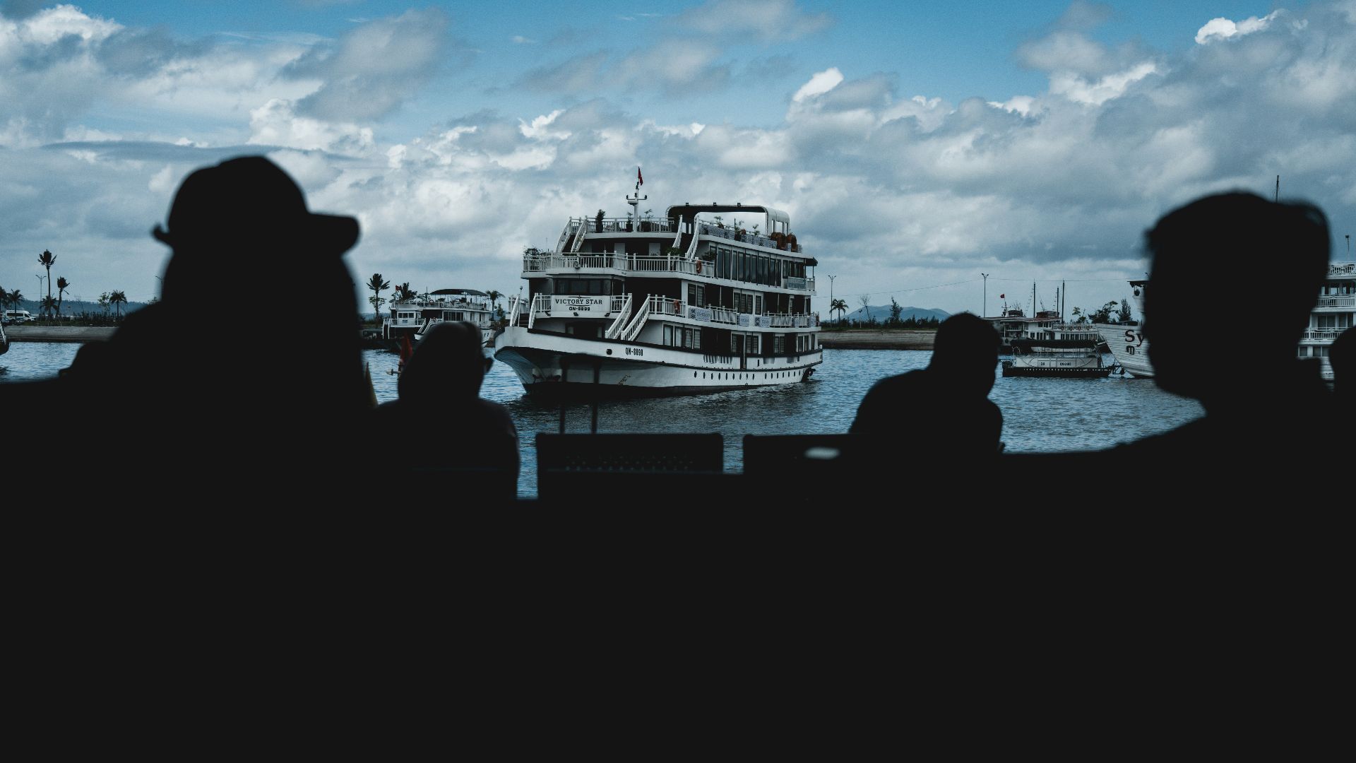 People silhouetted against a boat on the water