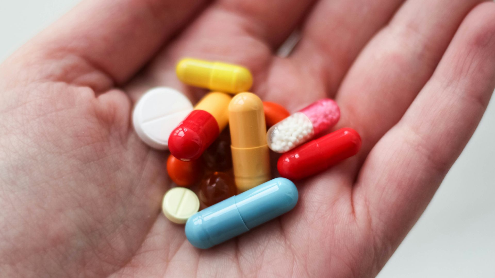 orange and white medication pill on persons hand