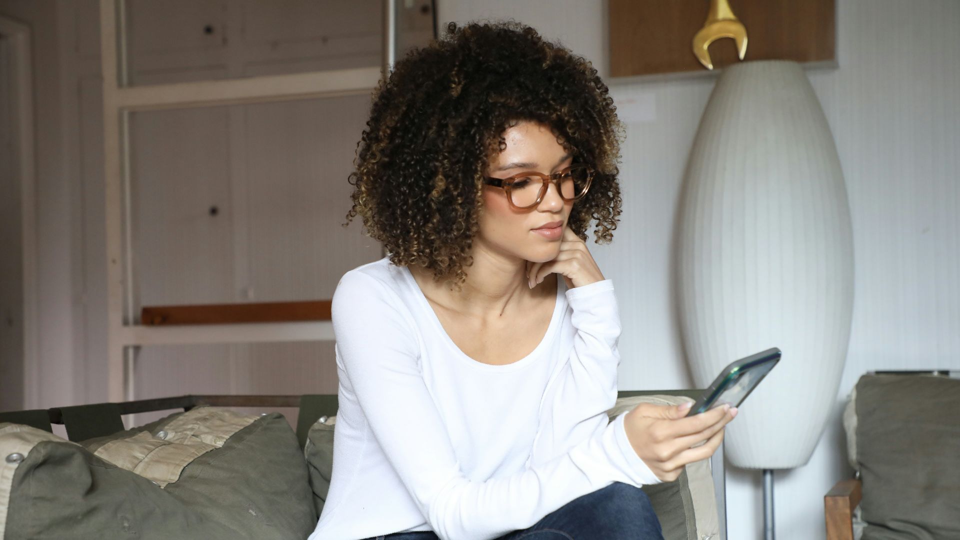 woman in white long sleeve shirt and blue denim jeans sitting on bed