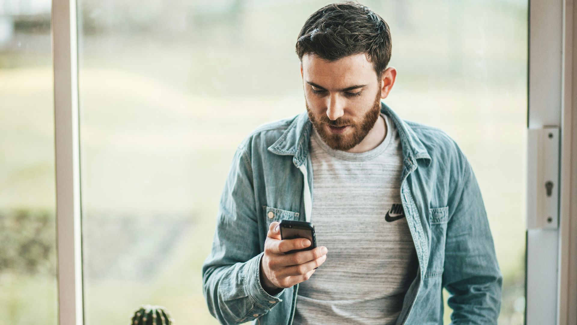 man holding a smartphone near the window