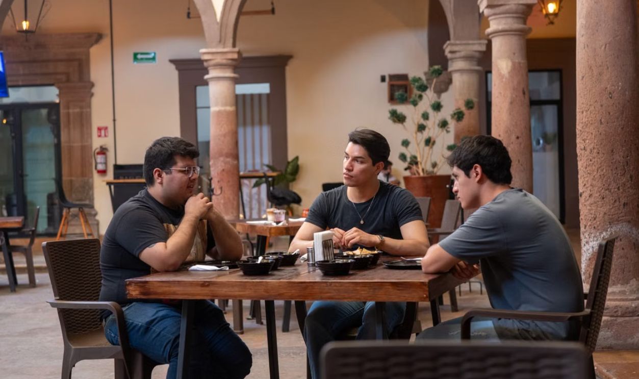 Three men enjoying Mexican food at an indoor courtyard restaurant in Guanajuato, Mexico
