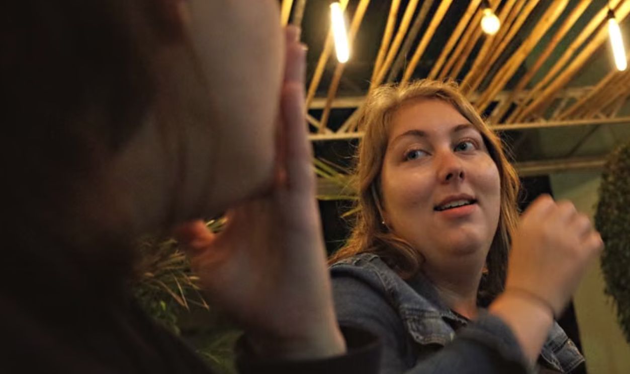 Three adults enjoying a casual meal together in a cozy indoor setting with warm lighting