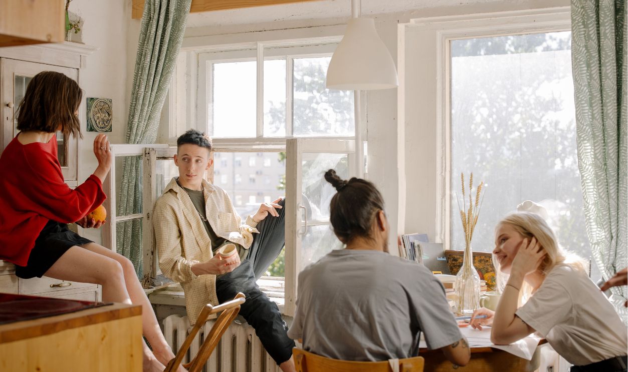 Group of young friends relaxing and chatting in a sunlit kitchen