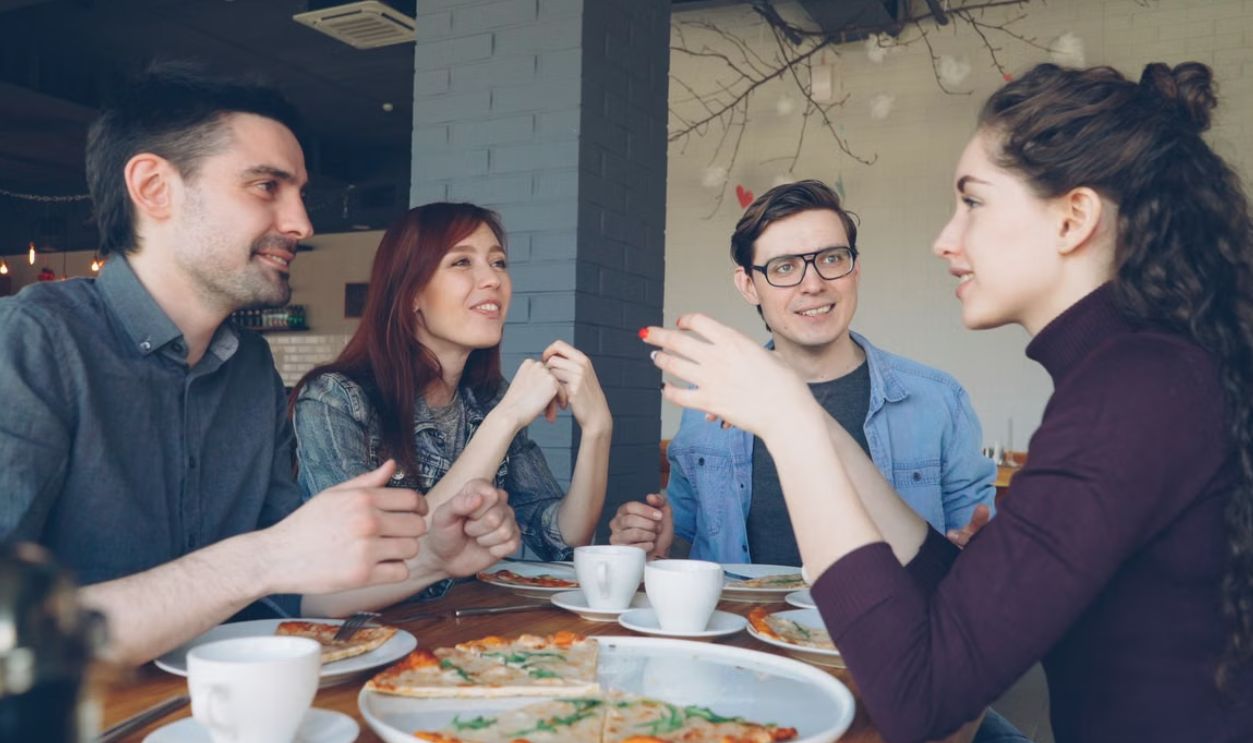 Friends having a delightful conversation over pizza and coffee in a cozy cafe