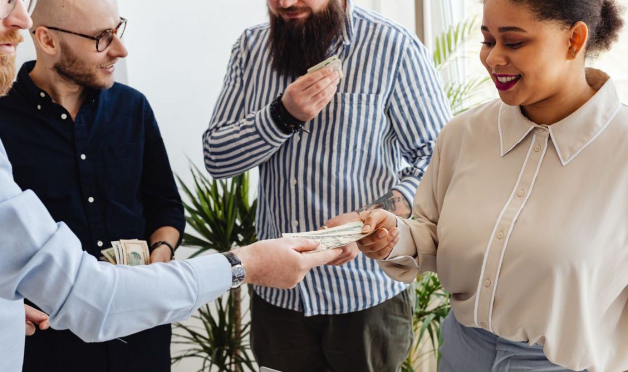 Business professionals exchanging money in a casual office setting