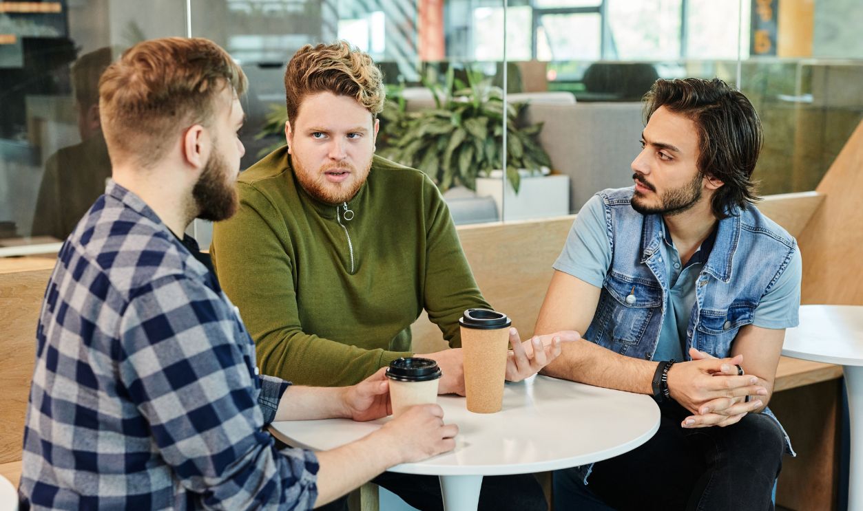 Three men having a casual business meeting in a cafe, engaging in conversation 