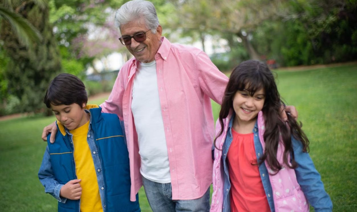 Happy grandfather bonding with grandchildren in a lush park, enjoying a joyful day outdoors.