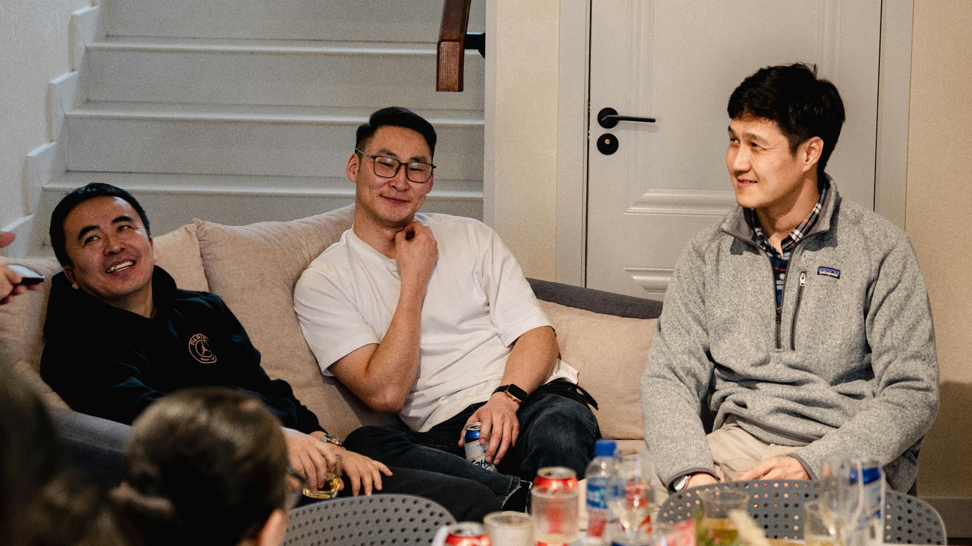 Three men sitting on a couch talking
