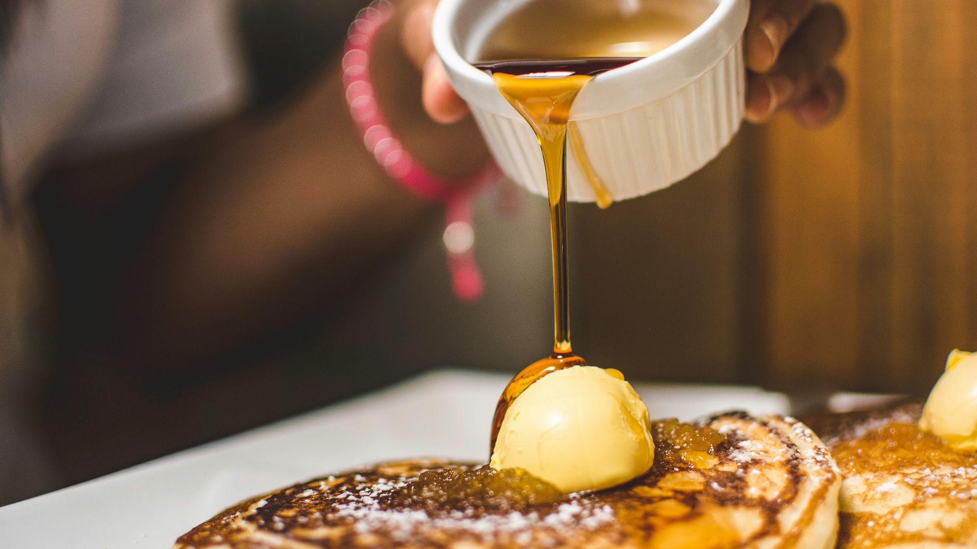 person pouring syrup into pancake