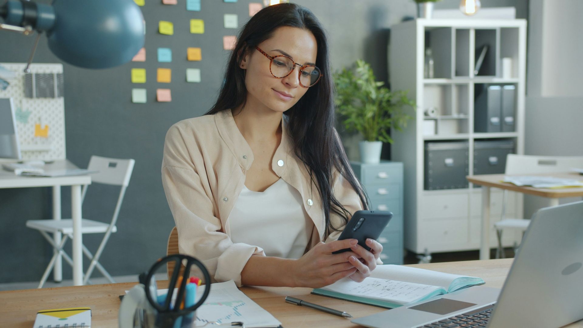 Woman working on a smartphone at her desk.