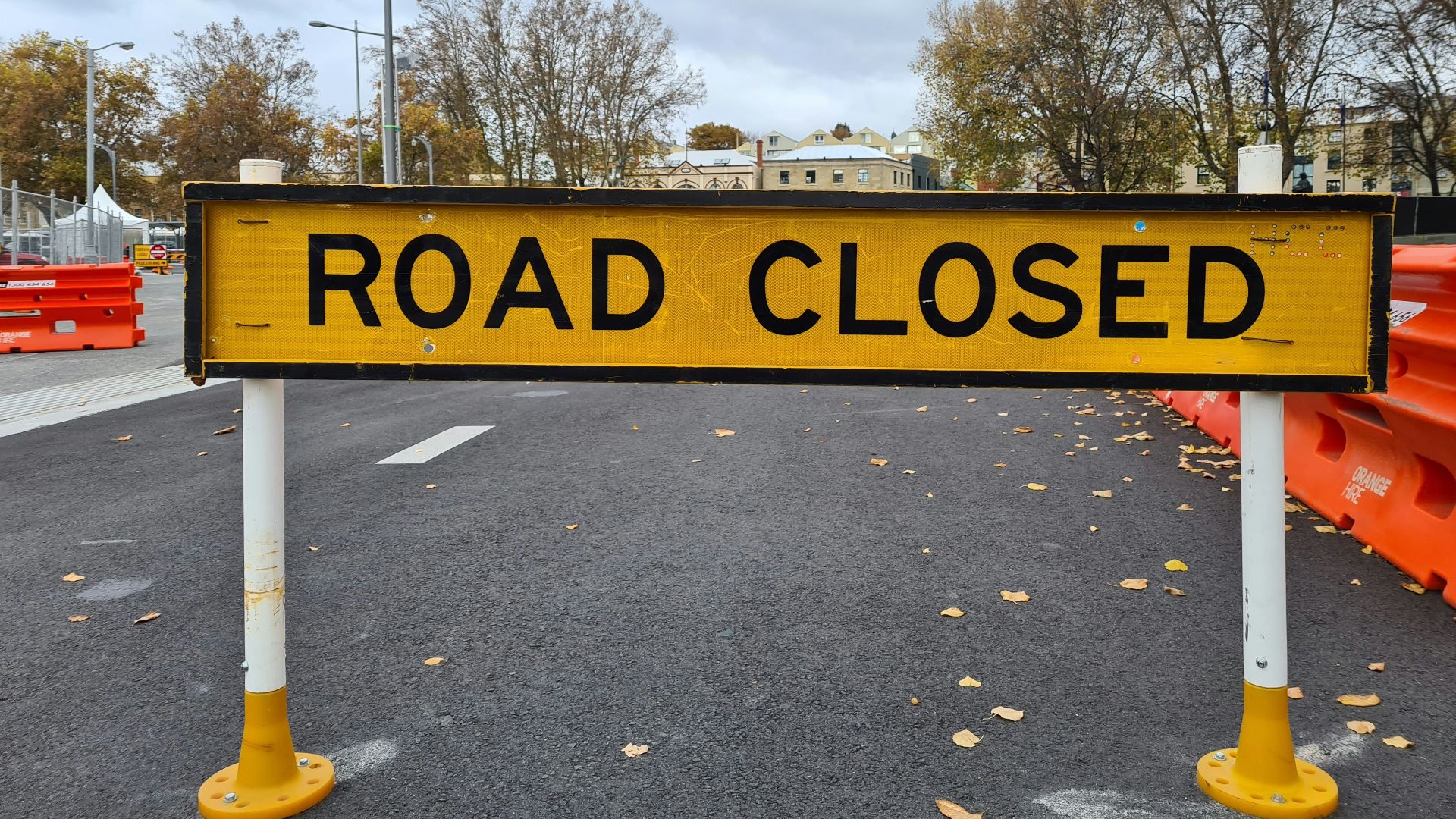 a yellow road closed sign sitting on the side of a road