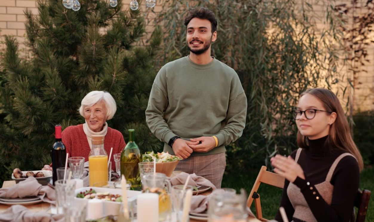 A diverse family enjoying a meal together outdoors, showcasing warmth and togetherness.