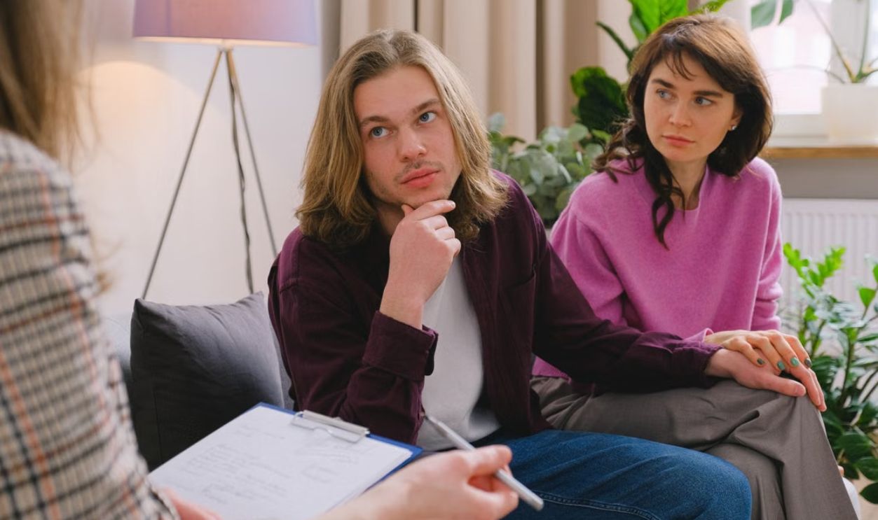 A couple holding hands during a therapy session in an office setting.