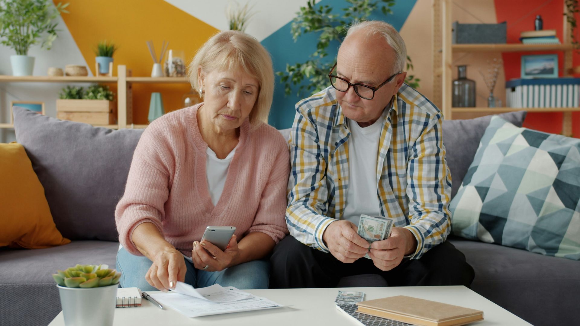 Elderly couple looking at bills and phone