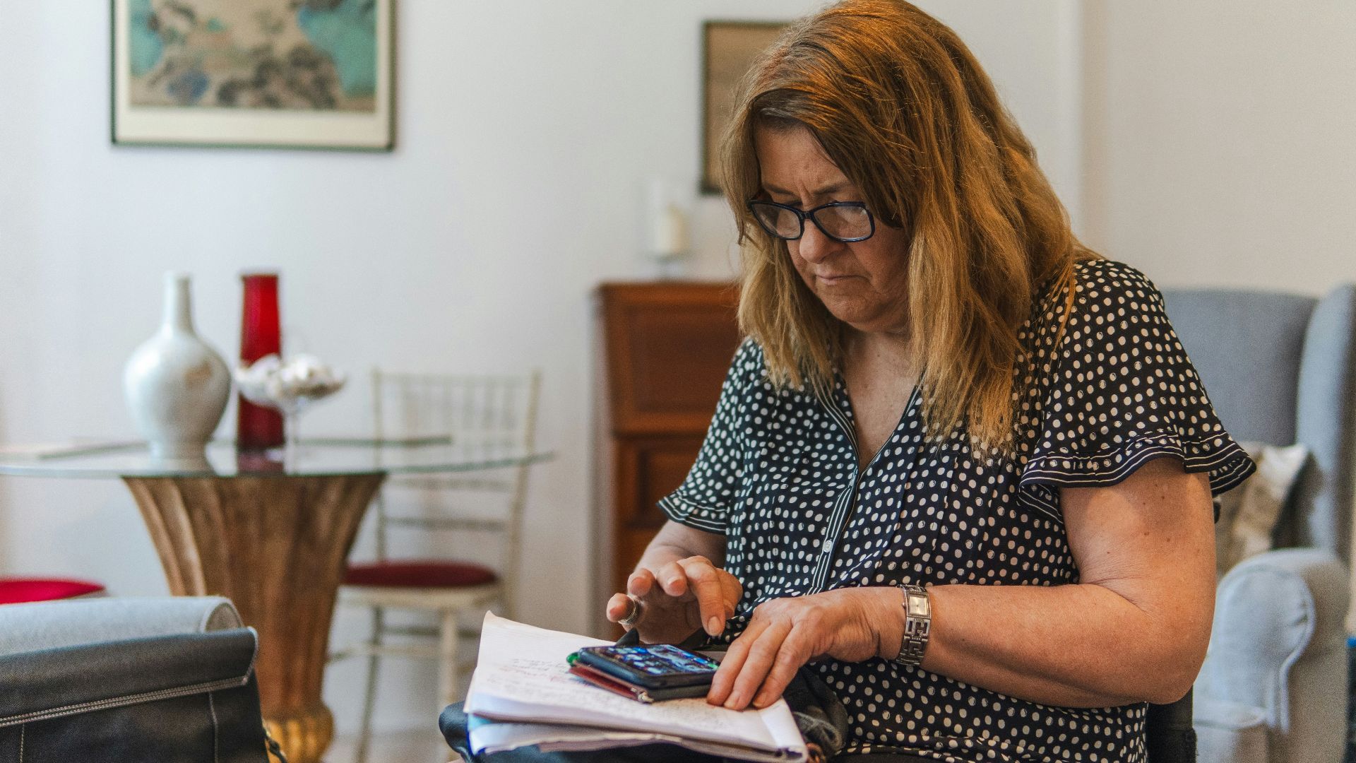 Woman using calculator with papers on table.