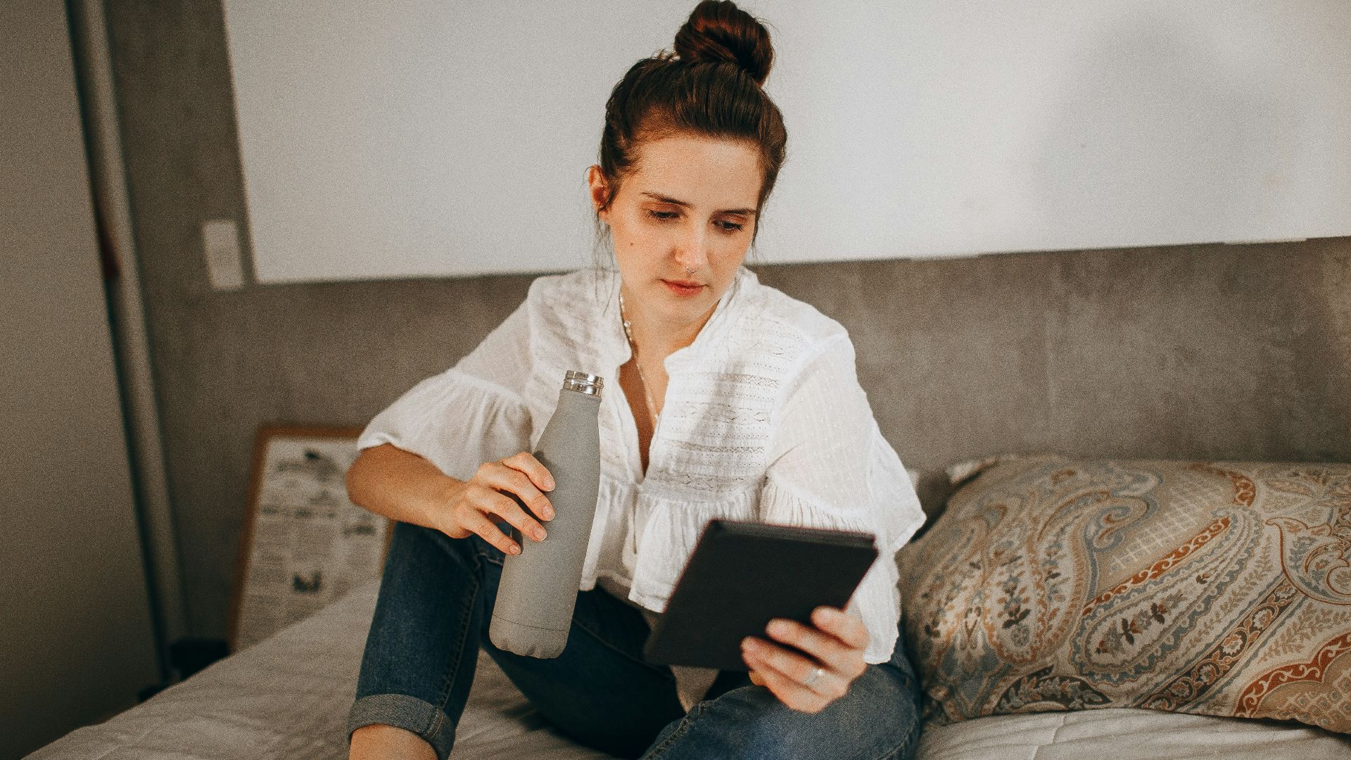 woman in white dress shirt and blue denim jeans sitting on brown sofa