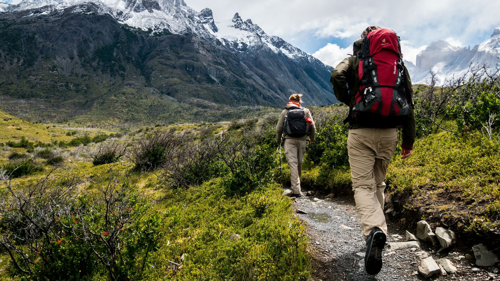 two person walking towards mountain covered with snow