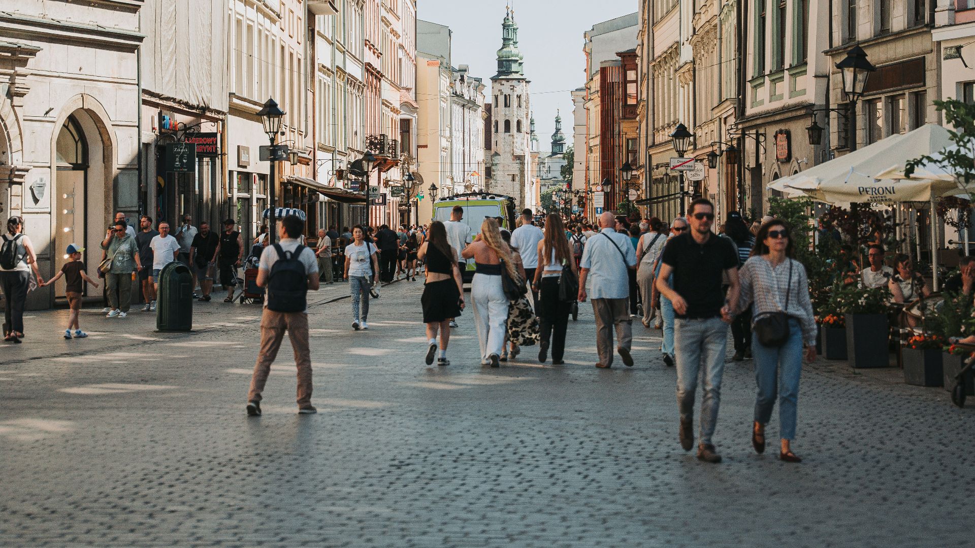 Sunny city street with pedestrians and colorful historic architecture.
