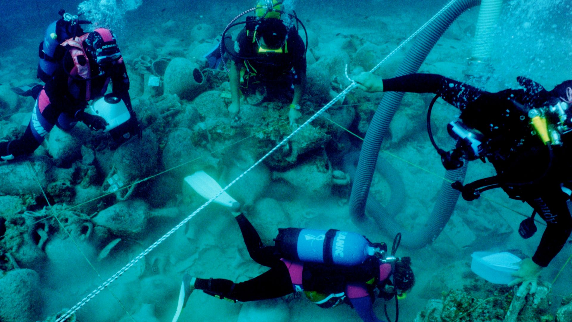 Diving archaeologists excavating the Alonnisos shipwreck in fall 2000, trench Θ3. The 2x2 m rope grid and airlift are visible.