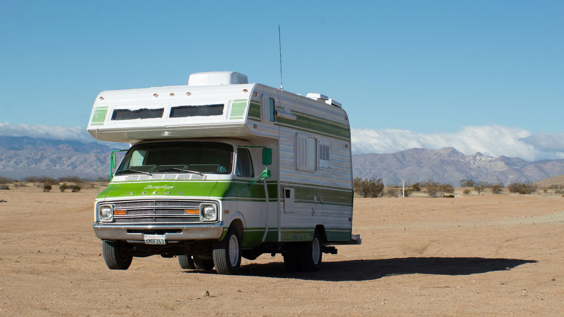 white and green rv on brown field under blue sky during daytime
