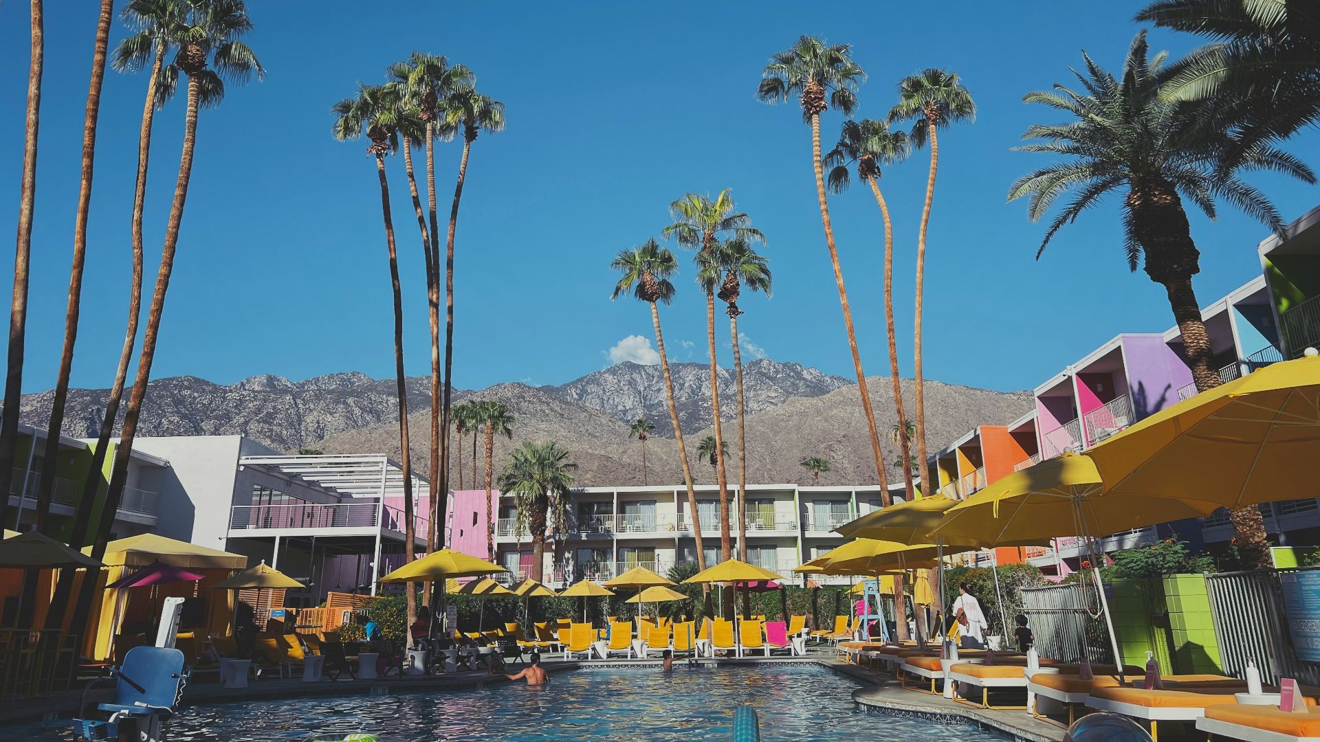 a pool with palm trees and buildings by it