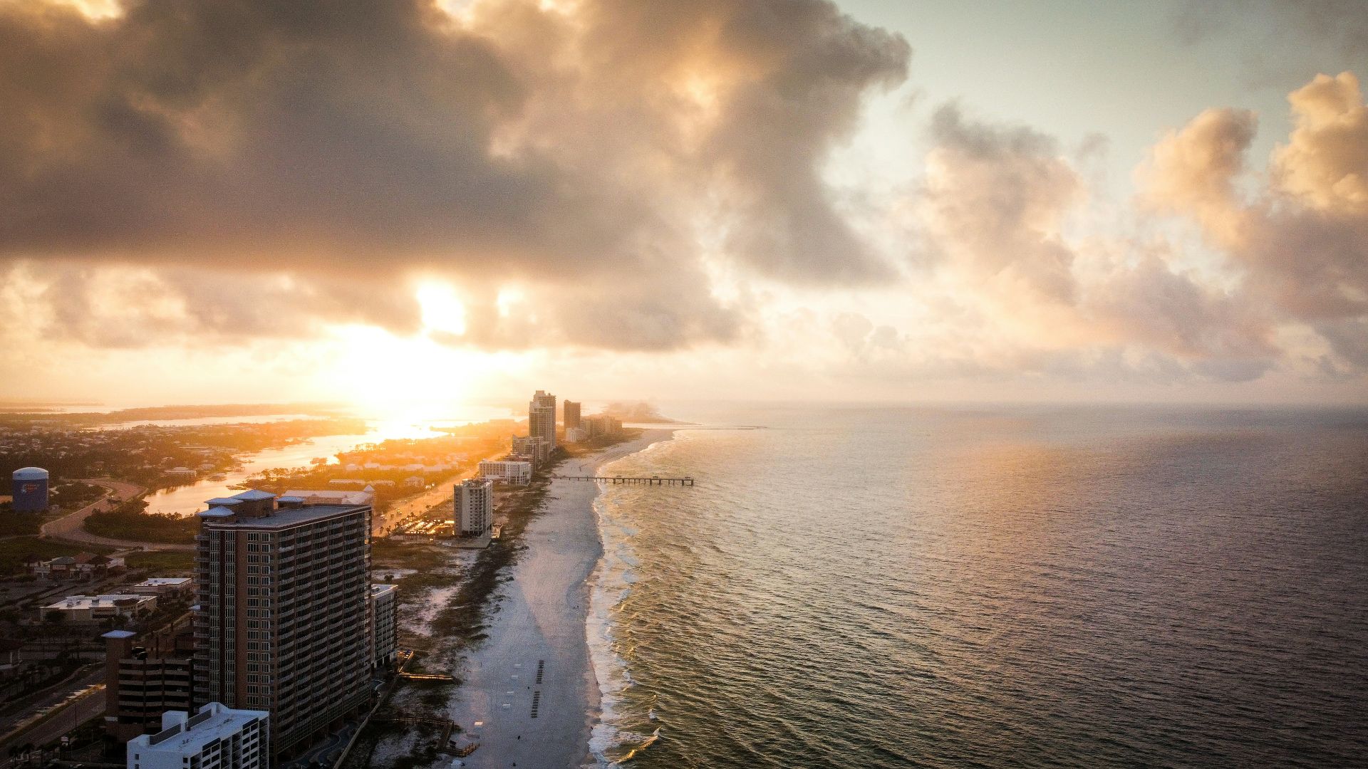 the sun is setting over the ocean and a city