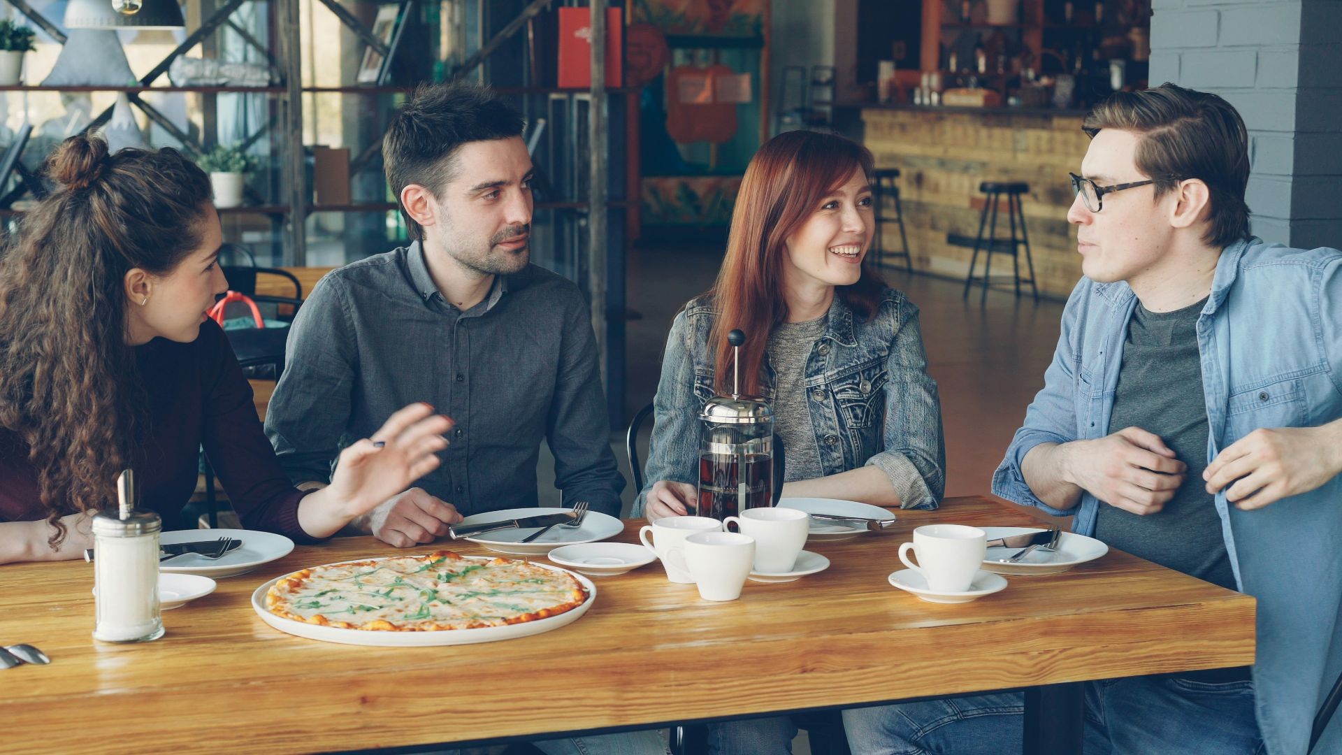 Friends are sharing pizza and conversation at a restaurant.