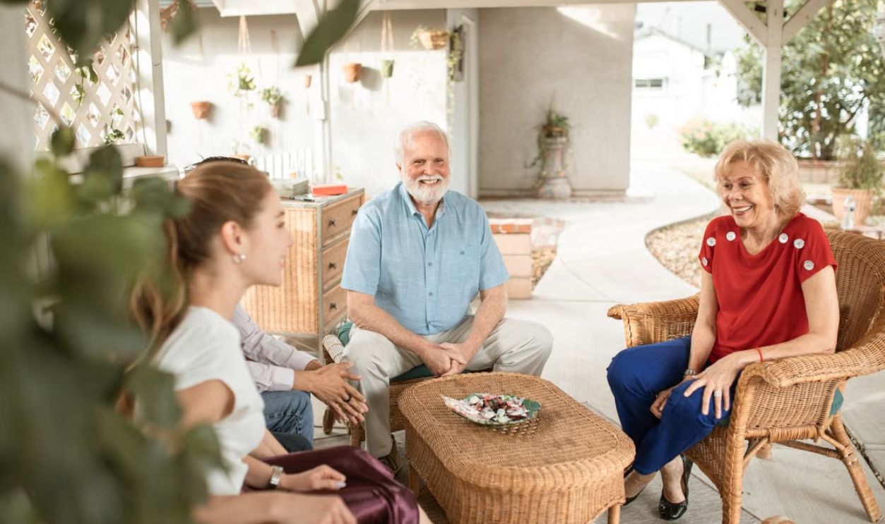 Family enjoying a relaxed conversation on a cozy outdoor patio with natural light.