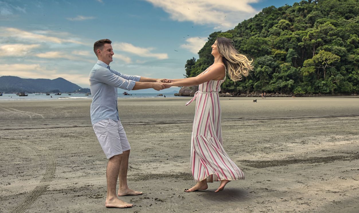 A happy couple dances barefoot on a sandy tropical beach