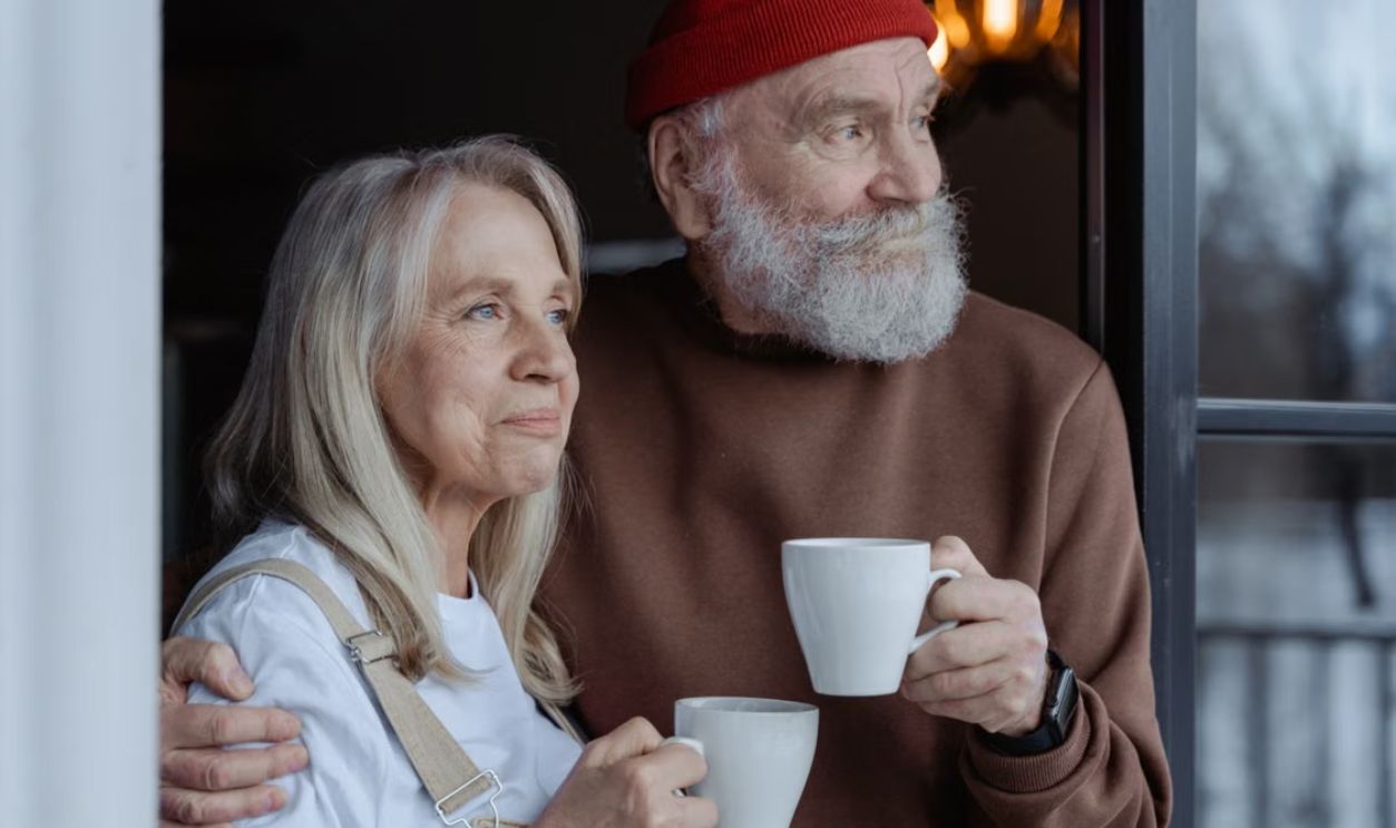 A senior couple embraces while enjoying coffee, symbolizing love and companionship.