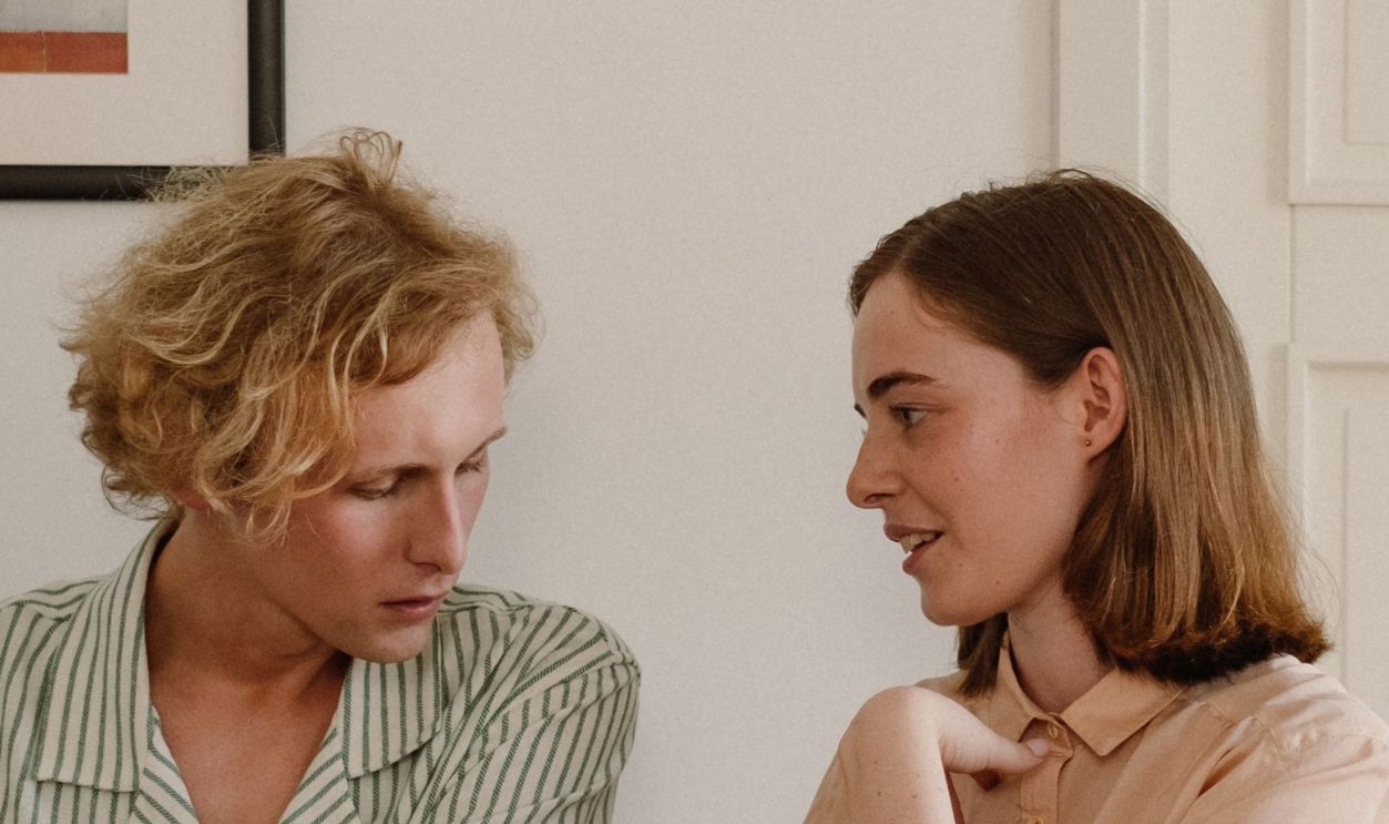 A couple engages in conversation by a piano