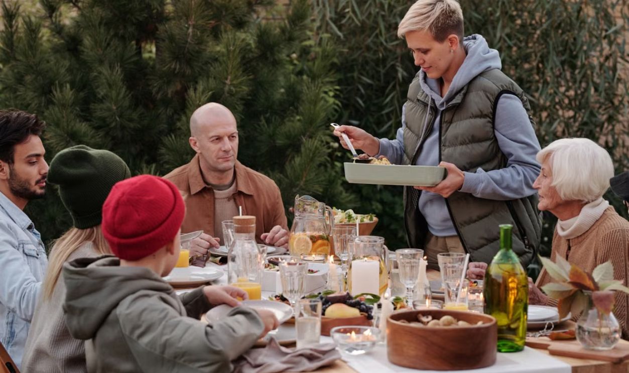 A cheerful multi-generational family enjoying dinner outdoors in a cozy garden.