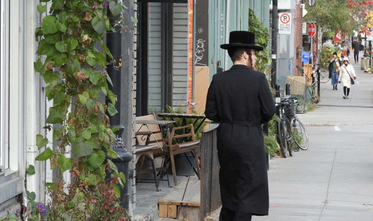 Montreal, Quebec, Canada-November 3, 2022: A Jewish man dressed in traditional garments walking in the Mile End District, Montreal.