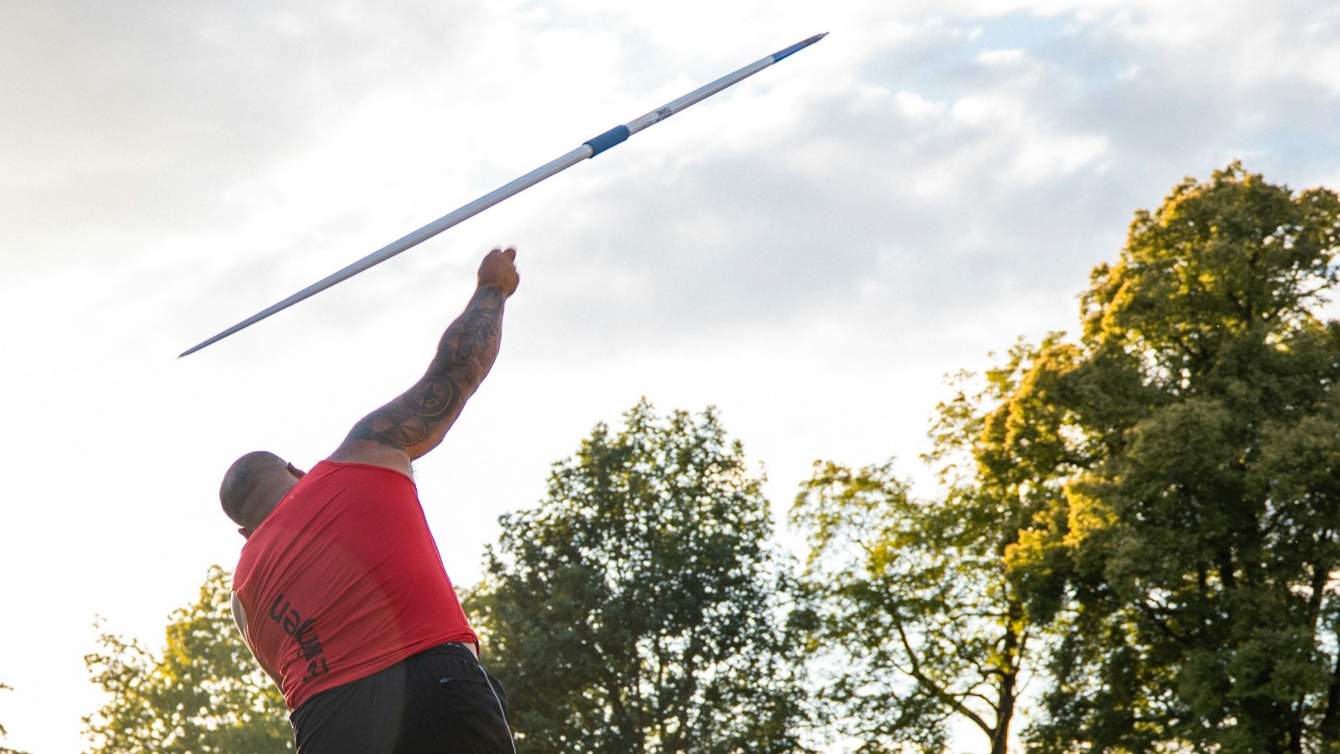 Athlete throwing a javelin on a track at sunset