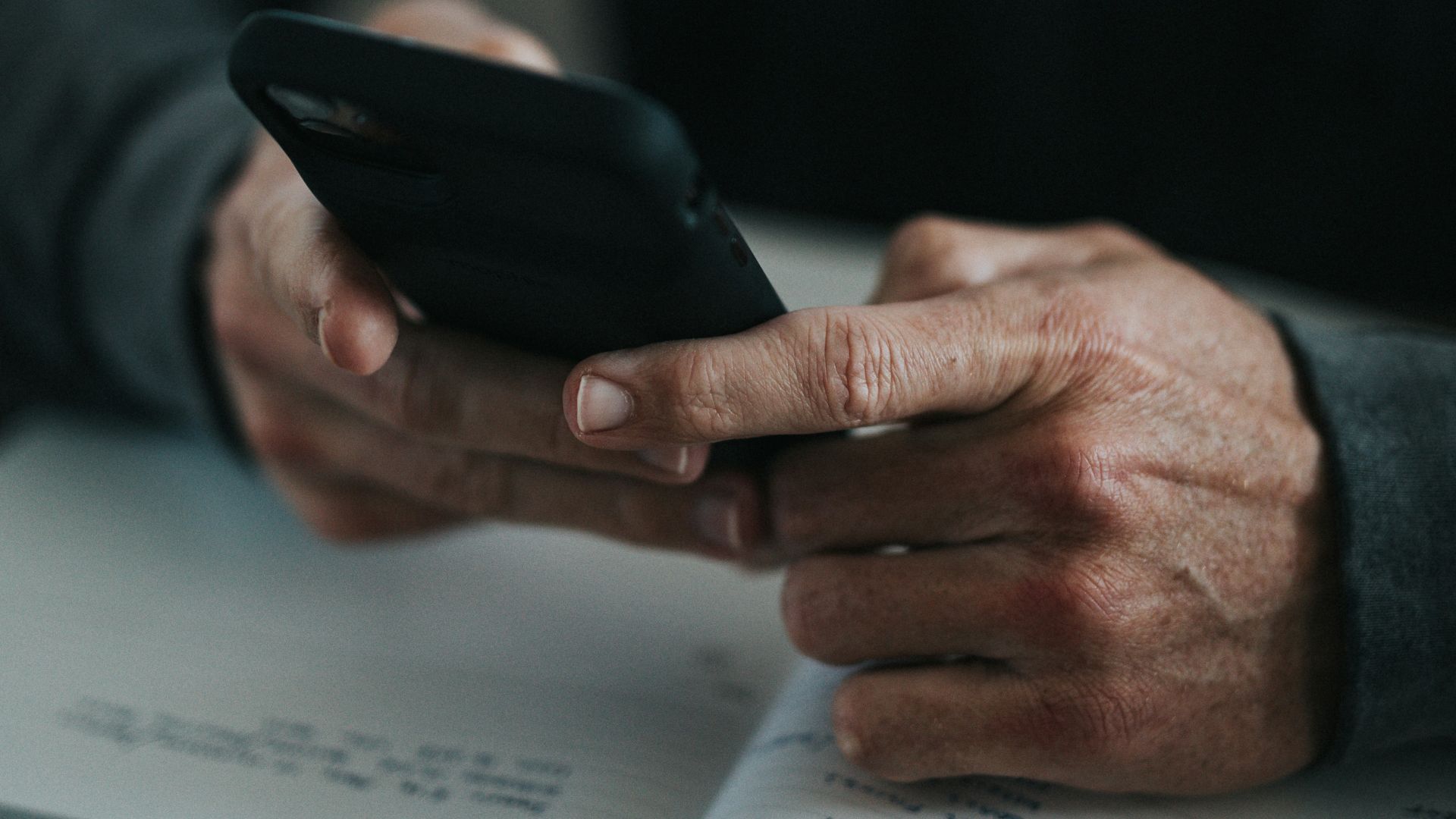 person holding black smartphone on white paper