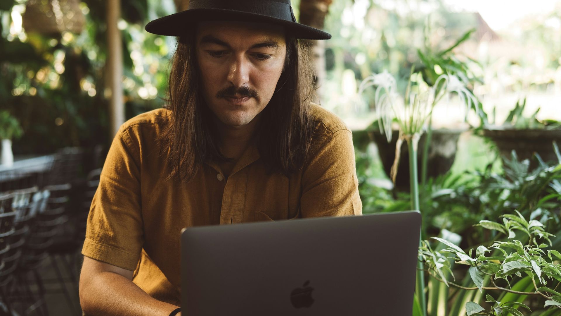 a man wearing a hat and using a laptop